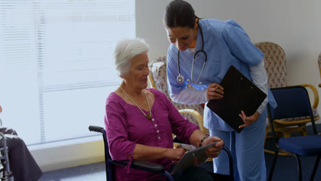 Vorderansicht-Einer-Kaukasischen-Ärztin-Und-Einer-älteren-Frau,-Die-Im-Pflegeheim-über-Ein-Digitales-Tablet-Diskutieren