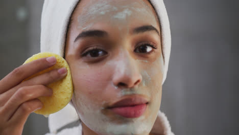 Close-up-of-mixed-race-woman-applying-face-mask-in-bathroom