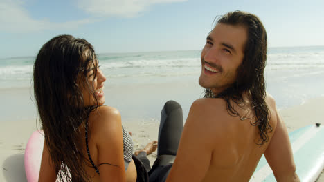 Surfer-couple-sitting-on-the-beach-4K-4k