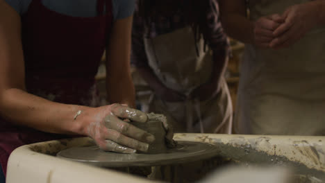 Mid-section-of-diverse-potters-creating-pottery-on-potters-wheel-at-pottery-studio