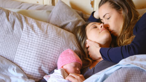 Lesbian-couple-romancing-while-relaxing-with-their-baby-boy-in-bedroom-4k