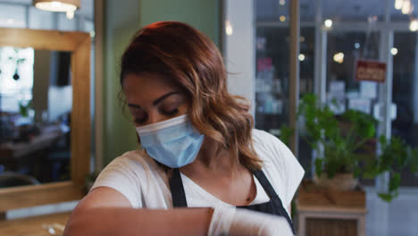 Female-hairdresser-wearing-face-mask-sneezing-on-her-elbow-at-hair-salon