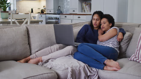 Mixed-race-lesbian-couple-sitting-on-couch-and-