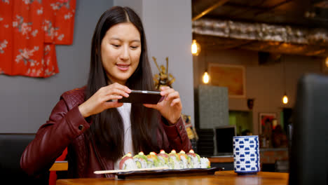 Woman-taking-photo-of-sushi-with-mobile-phone-4k