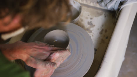 Close-up-view-of-male-potter-creating-pottery-on-on-potters-wheel-at-pottery-studio