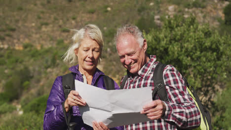 Happy-senior-couple-looking-at-map-in-moutains