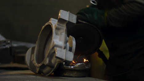 Close-up-of-worker-using-hand-grinder-machine-in-foundry-workshop-4k