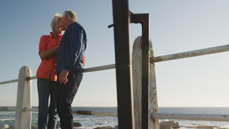 Senior-couple-embracing-each-other-alongside-beach