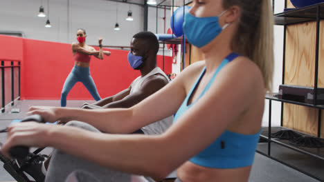 Diverse-group-wearing-face-masks-exercising-at-gym