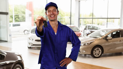 Caucasian-worker-wearing-a-blue-overwall-and-hat-in-a-car-distributor-giving-key-cars-and-smiling