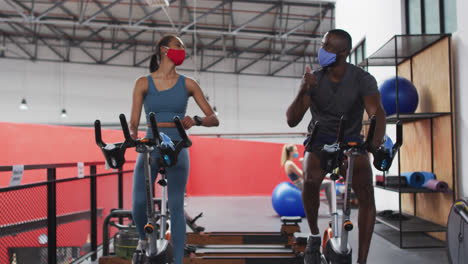 Man-and-woman-wearing-face-masks-touching-elbows-at-gym