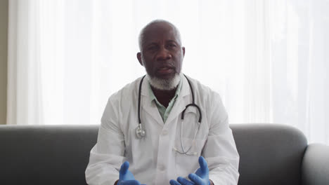 Porträt-Eines-Afroamerikanischen-Arztes,-Der-OP-Handschuhe-Trägt-Und-Während-Eines-Videoanrufs-Spricht