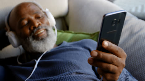 Senior-man-listening-music-on-mobile-phone-in-living-room-4k
