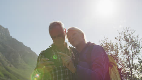 Senior-couple-searching-direction-on-smartphone-on-mountains