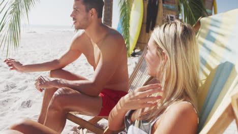 Caucasian-couple-sitting-on-sunbeds-on-the-beach