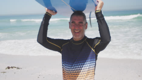 Senior-Caucasian-man-holding-a-surfboard-on-the-beach