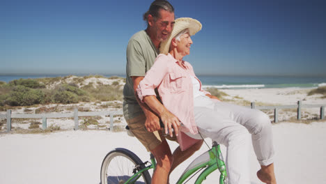Älteres-Kaukasisches-Paar,-Das-Fahrrad-Am-Strand-Fährt
