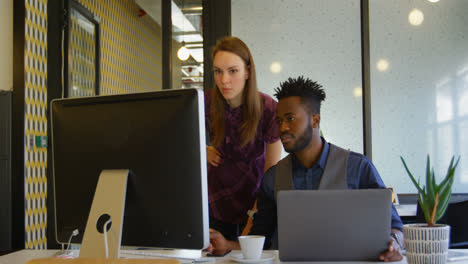 Front-view-of-young-cool-mixed-race-business-team-planning-and-working-at-desk-in-a-modern-office-4k