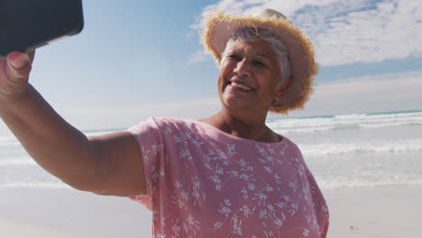 Ältere-Frau-Mit-Gemischter-Abstammung,-Die-Am-Strand-Ein-Selfie-Mit-Einem-Smartphone-Macht