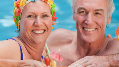 Portrait-of-caucasian-senior-couple-on-holiday-with-cocktail-in-swimming-pool