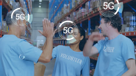 5g-text-over-round-scanners-against-team-of-diverse-volunteers-high-fiving-each-other-at-warehouse
