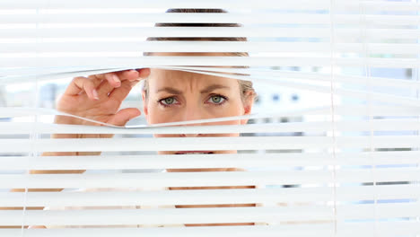 Stern-businesswoman-peeking-through-the-blinds