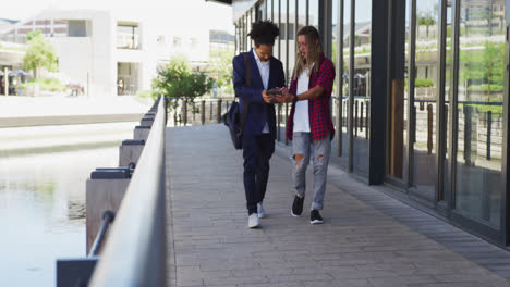 Two-diverse-male-friends-walking-in-the-street-using-a-digital-tablet