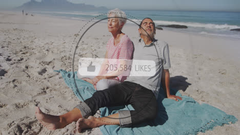 Animation-of-speech-bubble-with-thumbs-up-and-like-numbers-over-senior-couple-on-beach