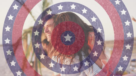 Animation-of-american-flag-circles-spinning-over-laughing-man-carrying-woman-piggyback-on-beach