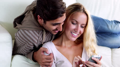 Glückliches-Junges-Paar,-Das-Auf-Der-Couch-Sitzt,-Während-Seine-Freundin-SMS-Schreibt