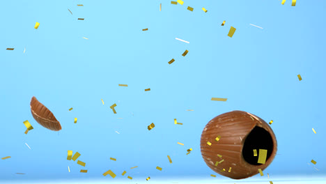 Animation-of-gold-confetti-over-chocolate-easter-egg-falling-and-breaking,-on-blue-background