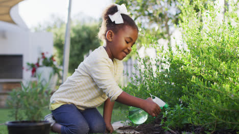 Feliz-Niña-Afroamericana-Haciendo-Jardinería,-Regando-Plantas-En-El-Jardín