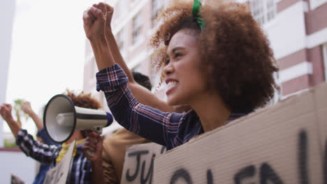 Grupo-Diverso-De-Hombres-Y-Mujeres-Sosteniendo-Pancartas-Gritando-Usando-Megáfono-Durante-La-Protesta