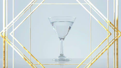 Golden-frame-design-pattern-over-olives-falling-into-cocktail-glass-against-grey-background