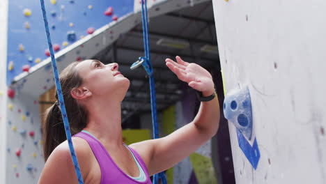 Nervous-caucasian-woman-preparing-to-climb-a-wall-at-indoor-climbing-wall