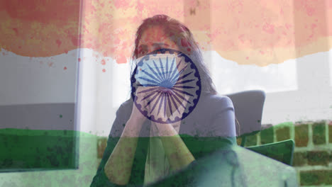 Composition-of-woman-wearing-face-mask-in-office-over-indian-flag