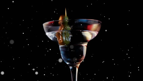 Animation-of-white-spots-falling-over-cocktail-glass-with-olives-on-black-background