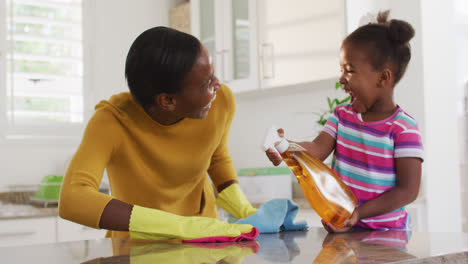 Afroamerikanische-Mutter-Und-Tochter-Putzen-Arbeitsplatten-Und-Lachen-In-Der-Küche