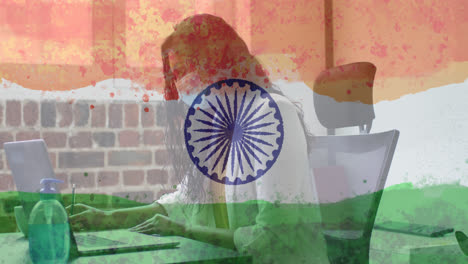 Composition-of-woman-wearing-face-mask-in-office-over-indian-flag
