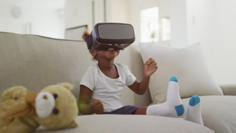 Glückliches-Afroamerikanisches-Mädchen,-Das-Zu-Hause-Mit-Einem-VR-Headset-Auf-Dem-Sofa-Liegt