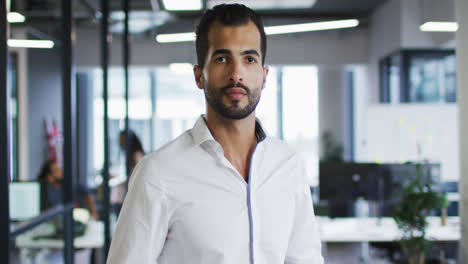 Portrait-of-mixed-race-businessman-standing-in-office-looking-to-camera