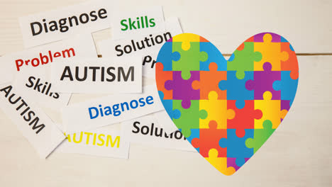 Animation-of-autism-text-over-heart-formed-with-autism-awareness-puzzles-on-white
