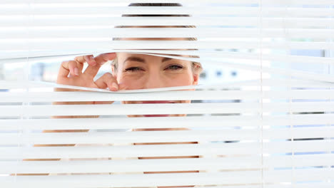 Surprised-businesswoman-peeking-through-the-blinds