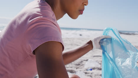 Mujer-Afroamericana-Recogiendo-Residuos-Plásticos-En-La-Playa.