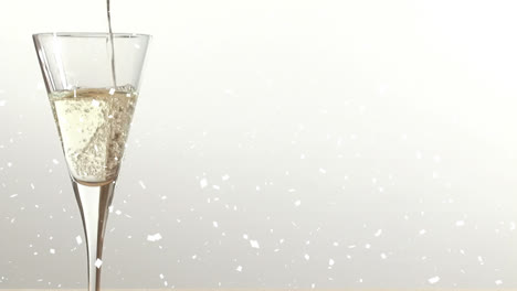 Animation-Von-Schnee,-Der-über-Ein-Champagnerglas-Auf-Weißem-Hintergrund-Fällt