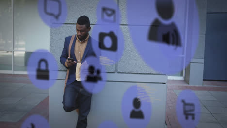 Mehrere-Digitale-Symbole-Gegen-Einen-Afroamerikanischen-Mann,-Der-Auf-Der-Straße-Ein-Smartphone-Benutzt