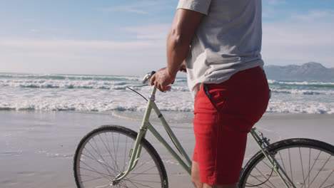 Senior-african-american-man-walking-with-a-bicycle-at-the-beach