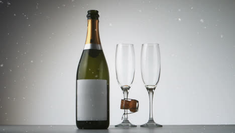 Animation-of-cork-falling-over-champagne-bottle-and-two-glasses-on-grey-background