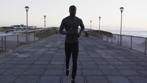 Focused-african-american-man-exercising-outdoors,-running-by-seaside