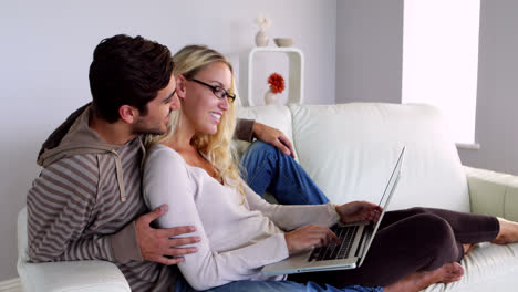 Glückliches-Junges-Paar-Sitzt-Auf-Der-Couch-Mit-Dem-Laptop